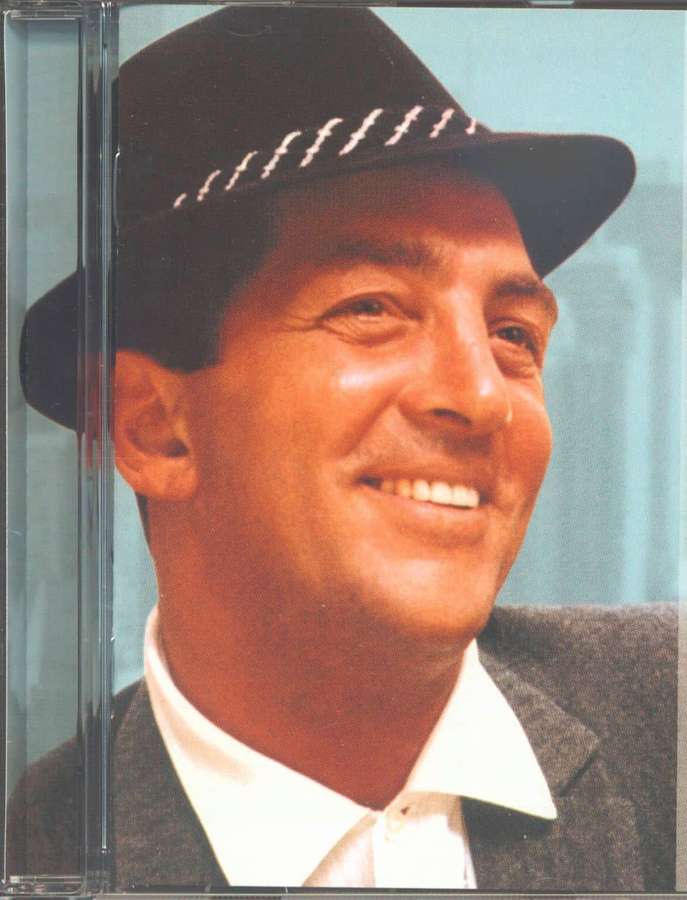 A smiling man wearing a black hat and suit against a blue backdrop. — Dean martin Background