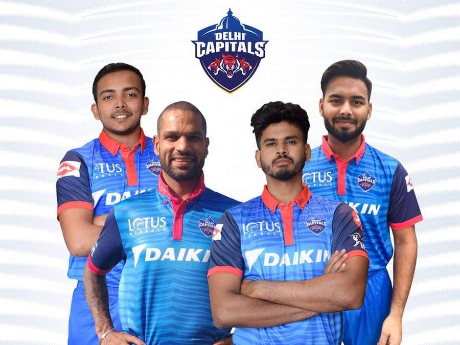 Four male cricket players in Delhi Capitals team jerseys posing for a team photo. — Delhi Capitals Wallpaper