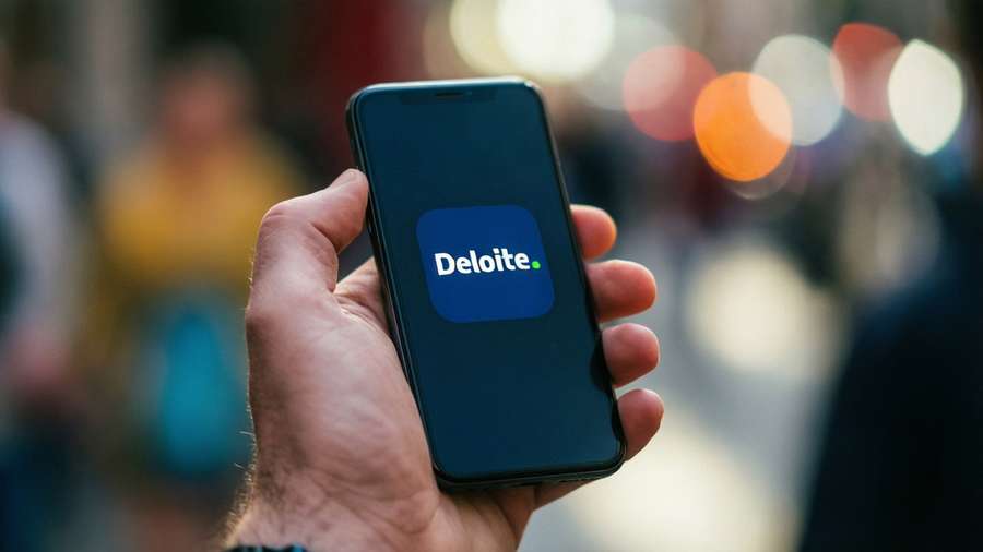Hand holding smartphone with glowing Deloitte app icon. — Deloitte Wallpaper