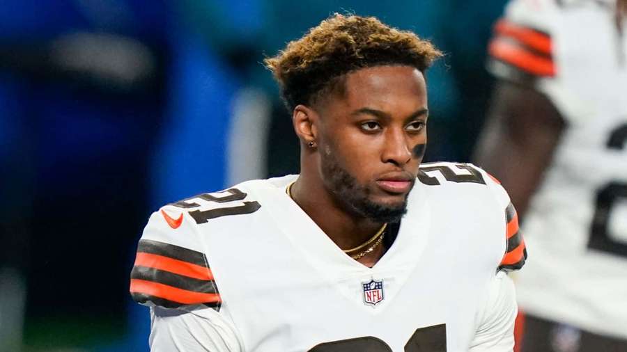 Cleveland Browns football player in white jersey with orange and brown stripes looking focused. — Denzel Ward Wallpaper