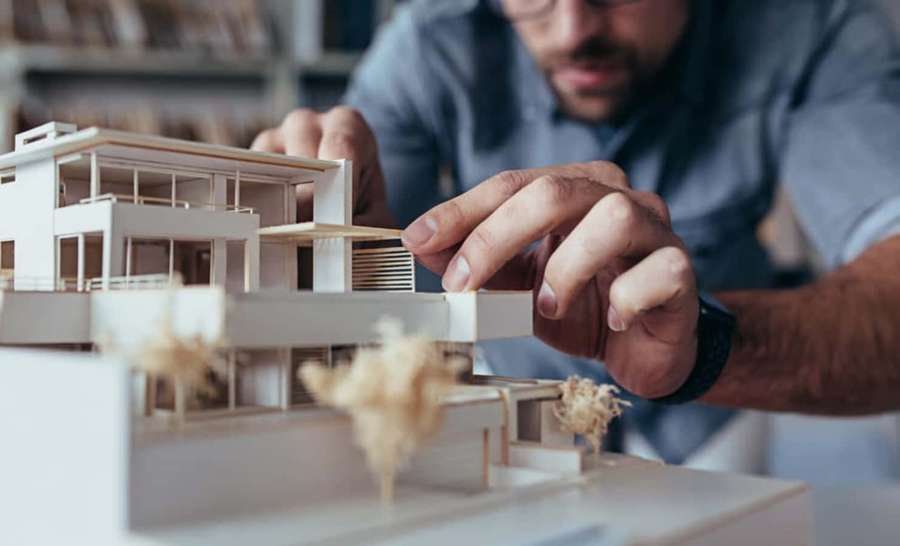 Architect working on a modern house model with wooden details. — Design Picture