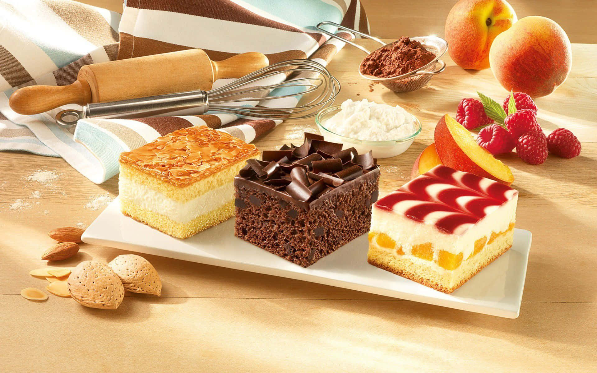 Three types of cake with fresh fruit and baking tools on a wooden table. — Dessert Background