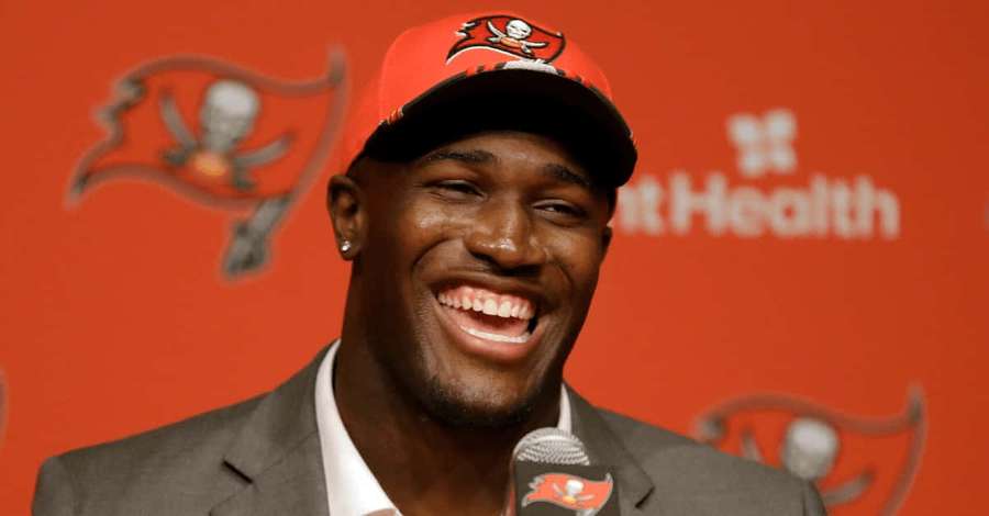 Jalkapalloilija Buccaneers-lippiksessä hymyilee lehdistötilaisuudessa. — Devin White Taustakuvat