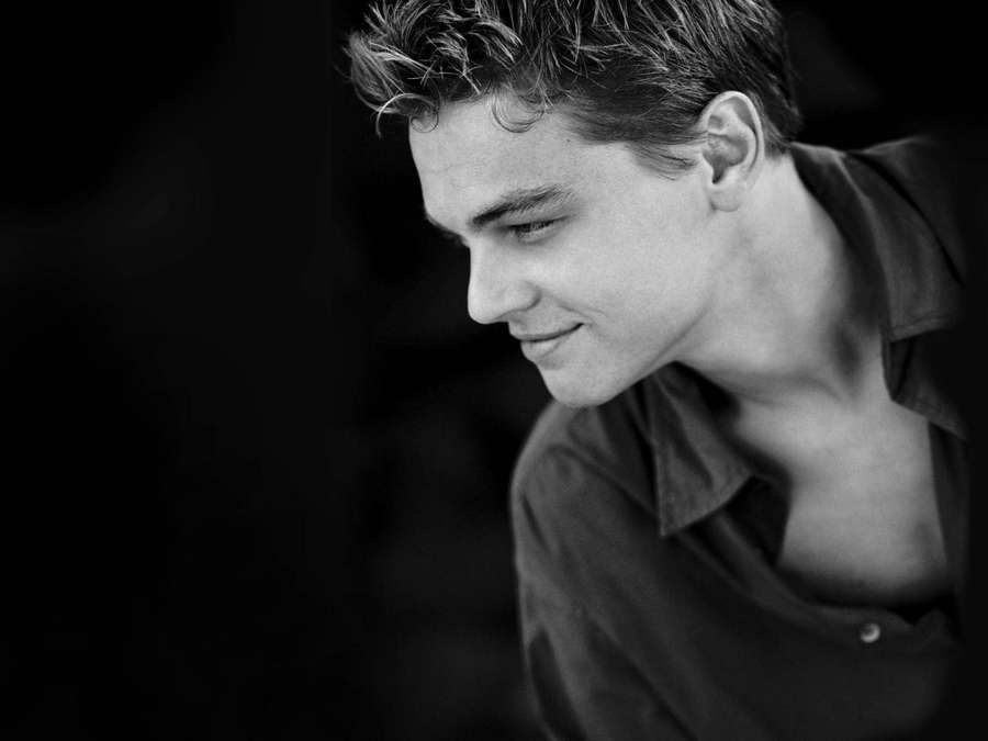 Young man smiling softly in a black and white studio portrait. — Dicaprio Wallpaper