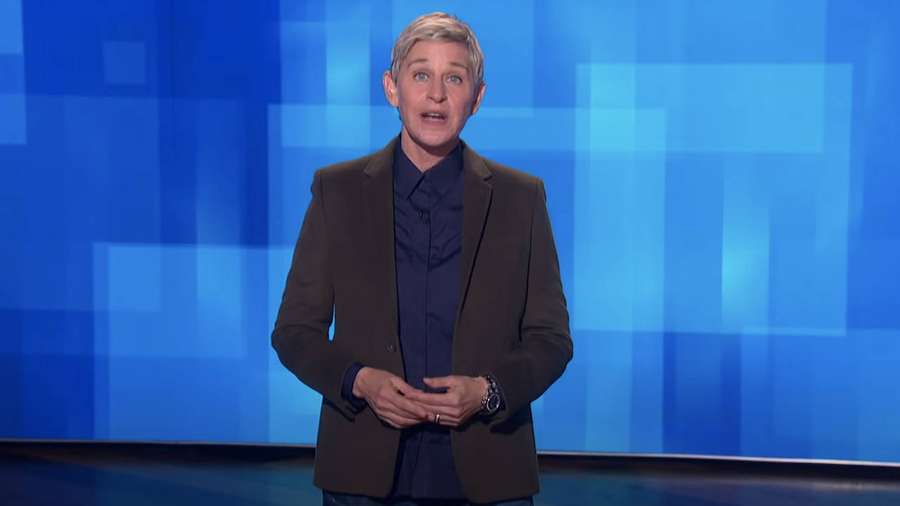 Ellen DeGeneres in einem Talkshow-Set mit blauem pixeligem Hintergrund. — Die Ellen Show Wallpaper