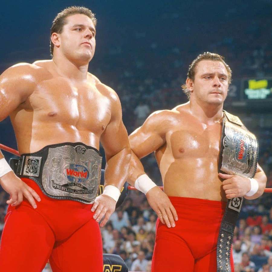 Dos luchadores en calzones rojos con cinturones de campeonato en un ring de lucha. — Dinamita Fondos de pantalla