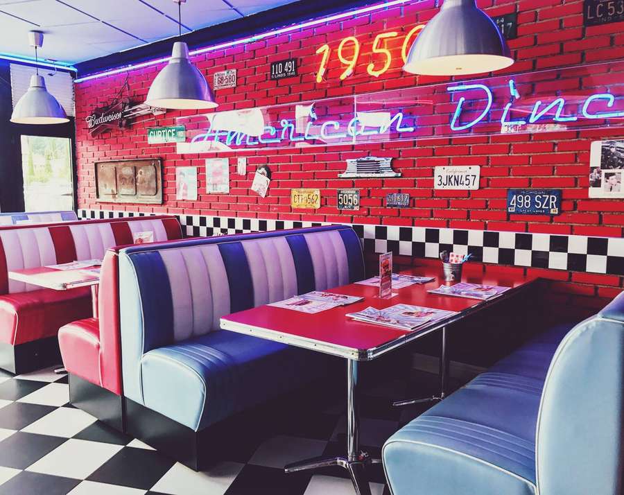 Retro American diner with red brick walls neon signs and checkered floors. — Diner Wallpaper