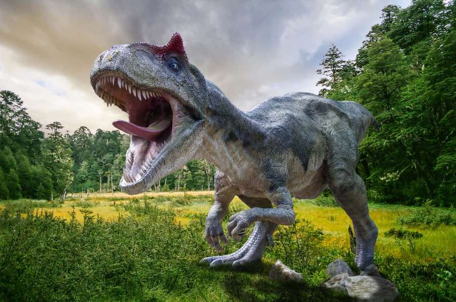 A roaring dinosaur in a forest clearing with green grass and trees. — Dinosaur Picture