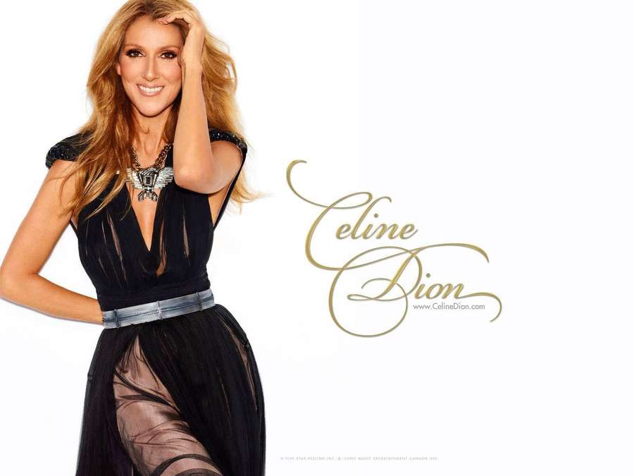 Celine Dion in a black dress smiling with one hand on her head. — Dion Wallpaper