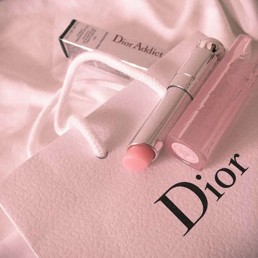 Pinker Dior Lippenstift auf einer pinken Dior Einkaufstasche mit Satinstoffhintergrund. — Dior Hintergrundbild