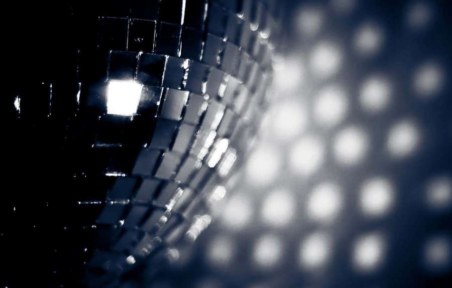 Shiny disco ball reflecting bright lights in a dark room. — Disco Background