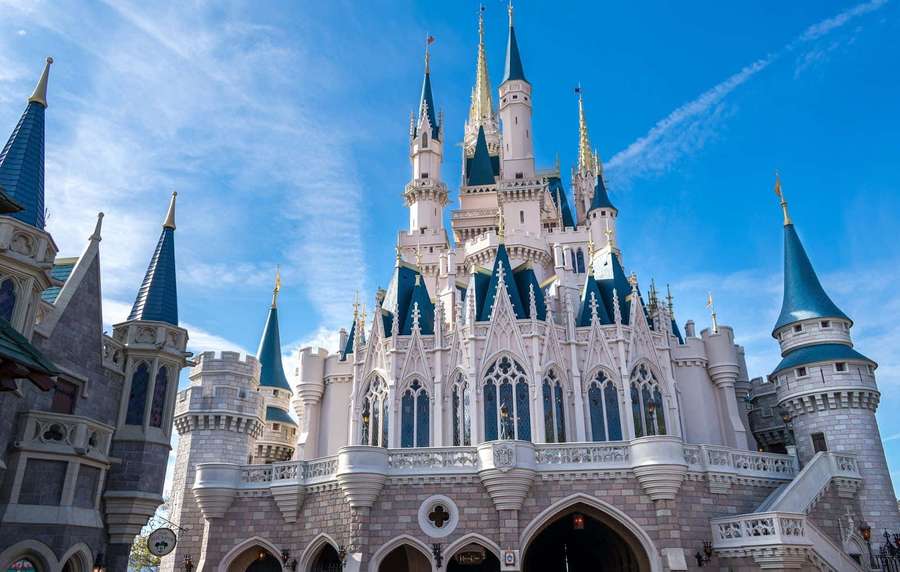 A majestic castle with blue spires and white stone towers under a clear blue sky. — Disney World Background