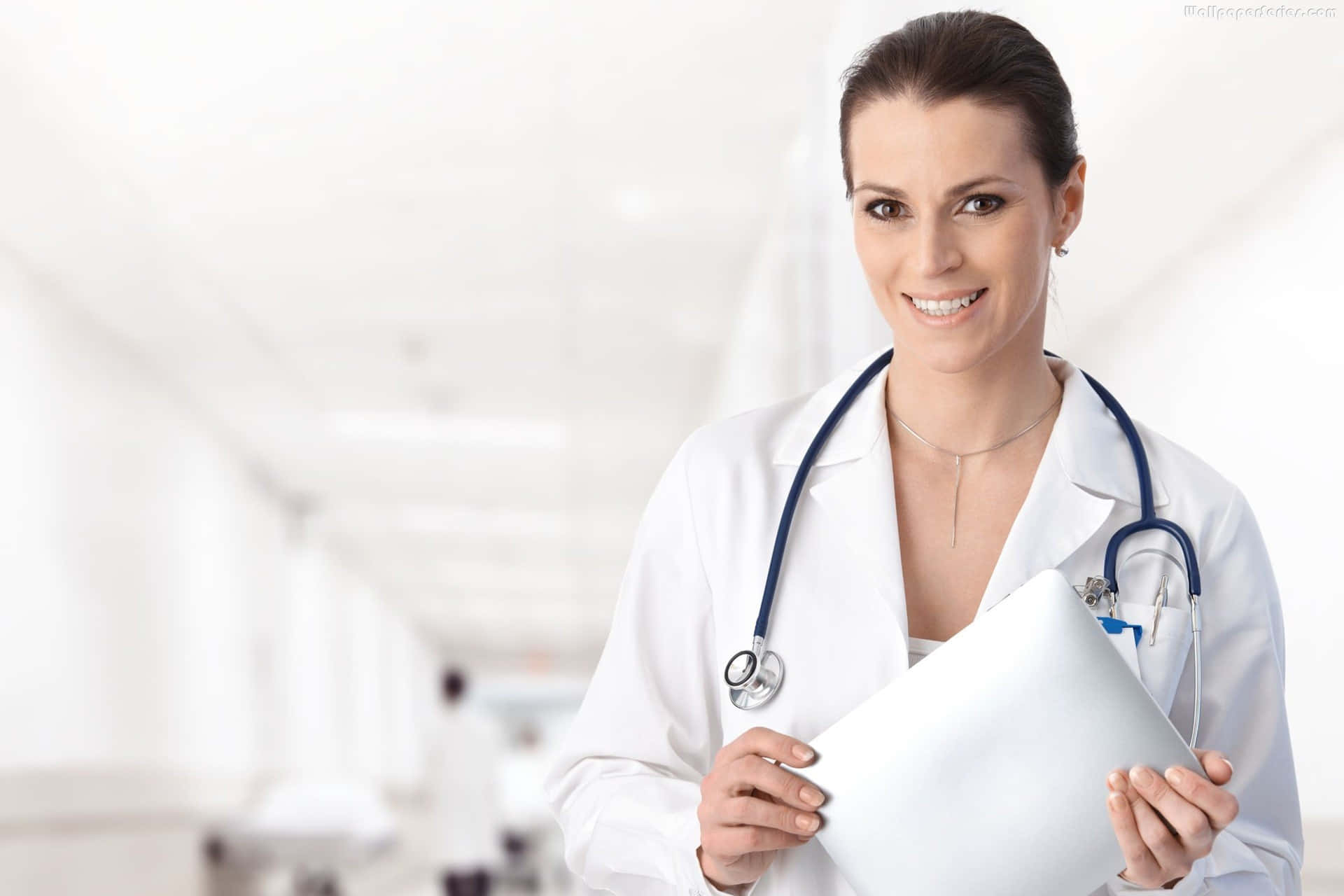 Doctora sonriente sosteniendo un portapapeles en el pasillo del hospital. — Doctor Fondos de pantalla