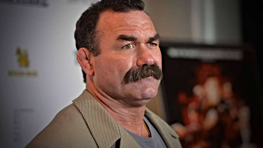 Man with thick mustache in checkered blazer at indoor event. — Don Frye Wallpaper
