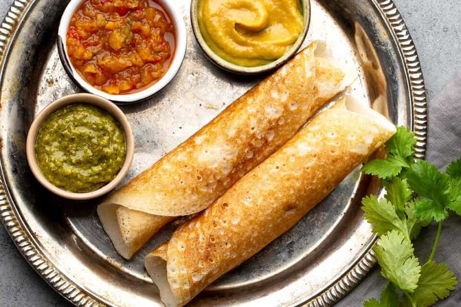 Two rolled dosas with chutneys and cilantro on a silver platter. — Dosa Wallpaper