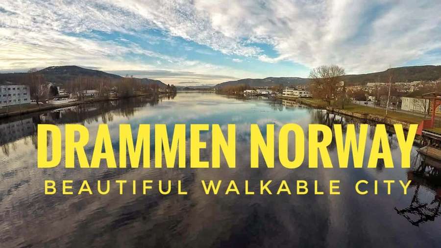 A river flows through Drammen Norway with buildings and hills visible under a partly cloudy sky. — Drammen Wallpaper