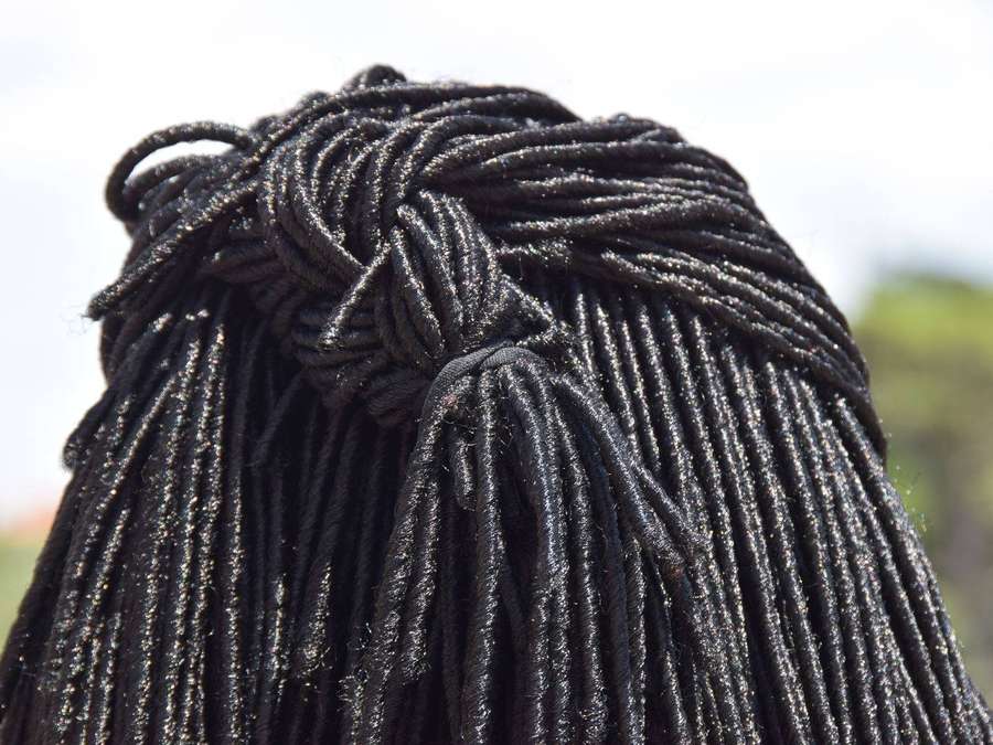 Close-up of black braided hair with a knot and loose strands in daylight. — Dreadlocks Background