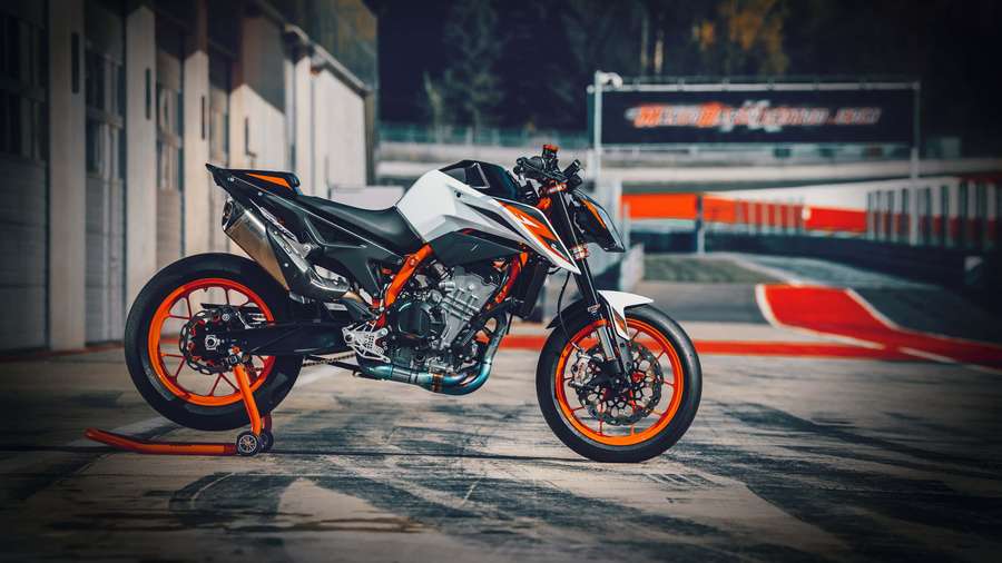 A sport motorcycle parked on a racetrack at dusk with orange accents. — Duke Background