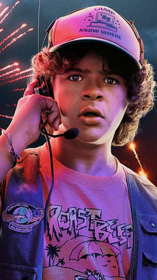 Poika 80-luvun leirivarusteissa pitelemässä kuulokkeita ilotulituksen keskellä. — Dustin Stranger Things Taustakuvat