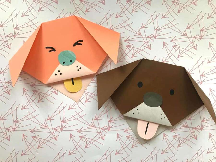 Two origami dog heads with painted eyes and tongues on a pink arrow pattern background. — Easy Dog Picture