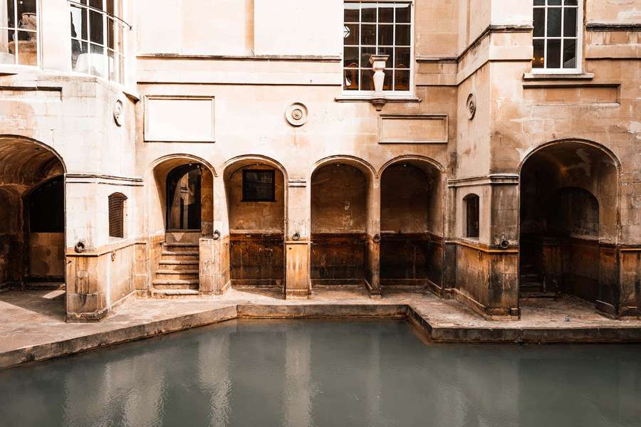 Históricas termas romanas de piedra con pasillos arqueados y agua gris tranquila. — Edad Media Fondos de pantalla