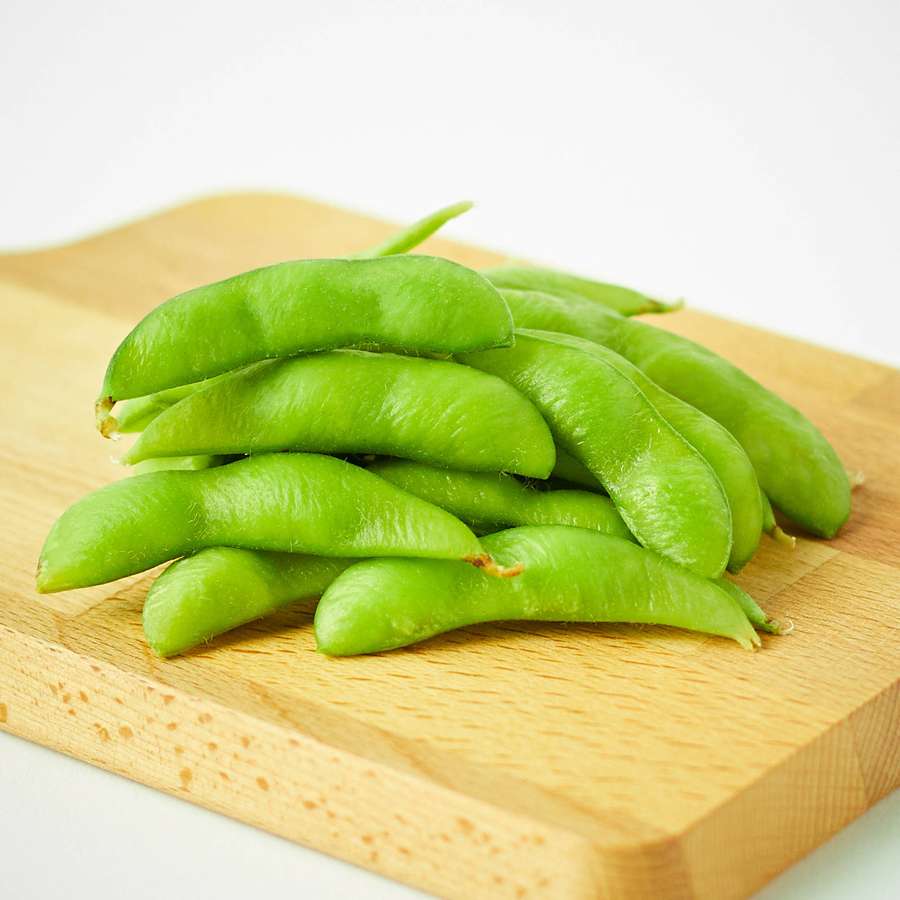 Tuoreita vihreitä edamame-palkoja puisella leikkuulaudalla. — Edamame Taustakuvat