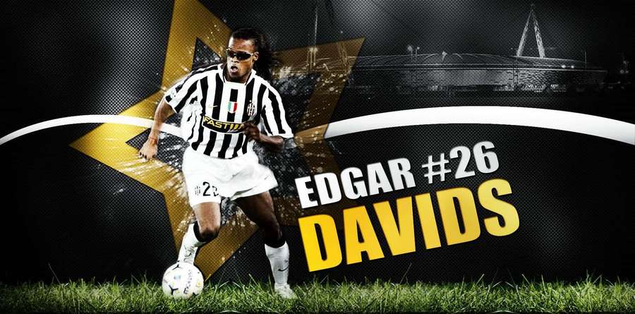 Soccer player Edgar Davids in action on grass with stadium background and bold text. — Edgar Davids Wallpaper