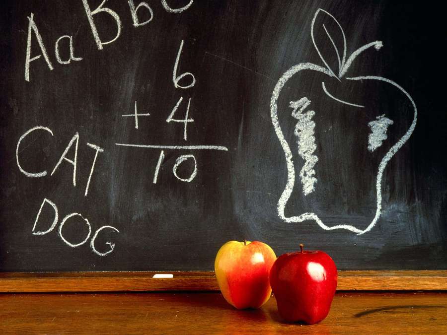 Two apples sit in front of a chalkboard with writing and a drawn apple. — Educated Wallpaper