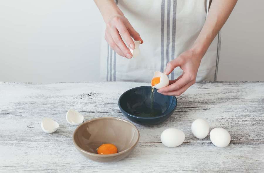 Person cracking eggs into bowls on a rustic wooden table. — Egg White Wallpaper