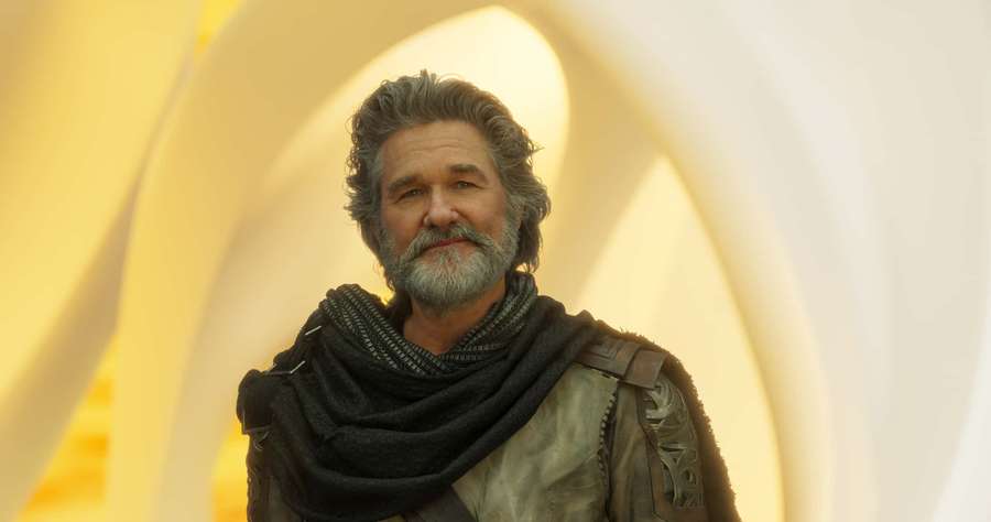 A gray-bearded man in futuristic armor stands in a glowing yellow tunnel. — Ego Wallpaper