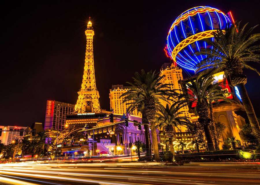 Las Vegas Nachtszene mit Eiffelturm-Nachbau und leuchtender Kugel, umgeben von Palmen und streifenden Lichtern. — Eiffel Bilder