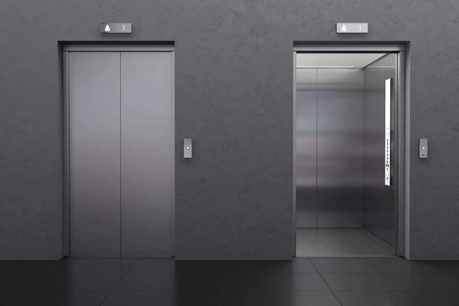 Two modern elevators one closed one open in a gray minimalist lobby. — Elevator Picture