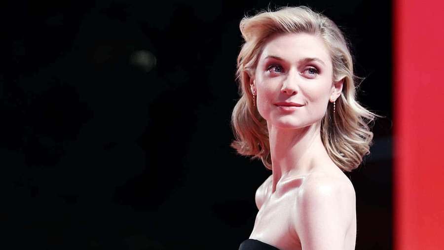 A woman with blonde hair and blue eyes smiles softly in a formal portrait. — Elizabeth Debicki Wallpaper