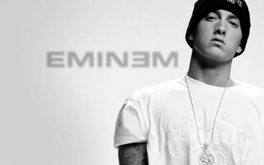 Eminem in a black and white studio portrait wearing a beanie and chain. — Eminem Background