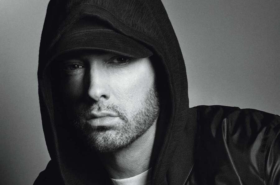 A man in a black hoodie stares intensely at the camera in a studio portrait. — Eminem Picture