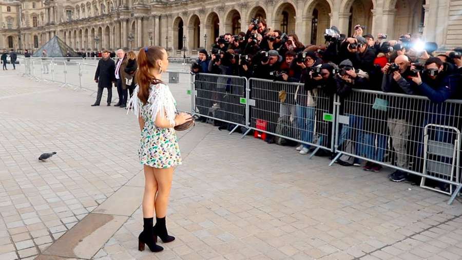 Eine Frau in einem Blumenkleid steht vor Fotografen im Louvre-Museum. — Emma Chamberlain Bilder