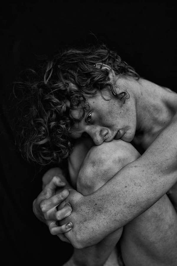 A person with curly hair hugs their knees in a tender, vulnerable pose. — Emotion Picture