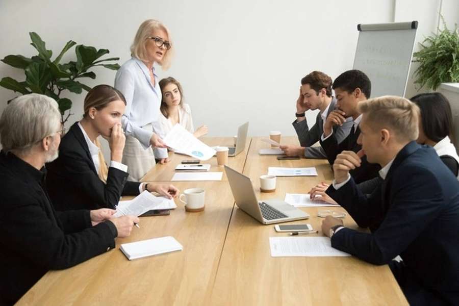 Business professionals in suits attending a meeting around a wooden table with laptops and documents. — Enterprise Wallpaper