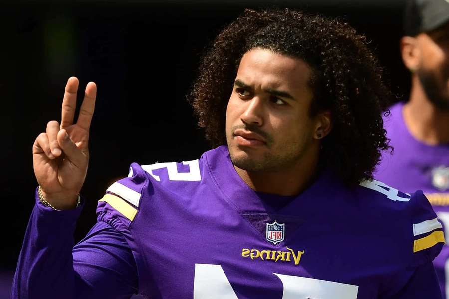 Football player in purple Vikings jersey making peace sign outdoors. — Eric Kendricks Wallpaper