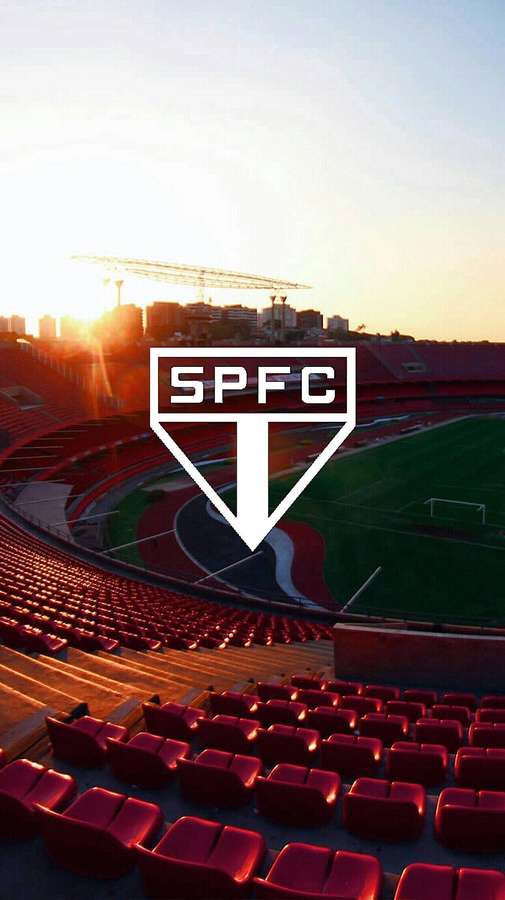 Estádio do SPFC ao pôr do sol com assentos vermelhos vazios e horizonte da cidade ao fundo. — Estádio Papéis de Parede