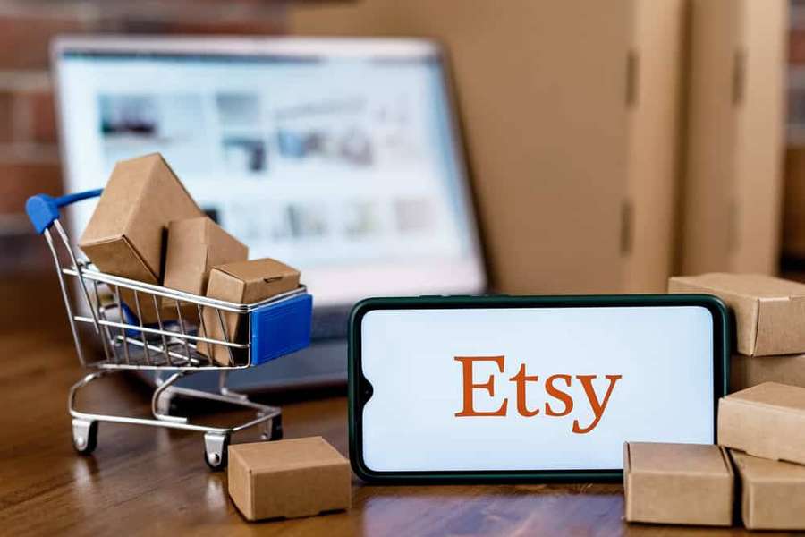 Smartphone showing Etsy app surrounded by cardboard boxes and miniature shopping cart. — Etsy Wallpaper