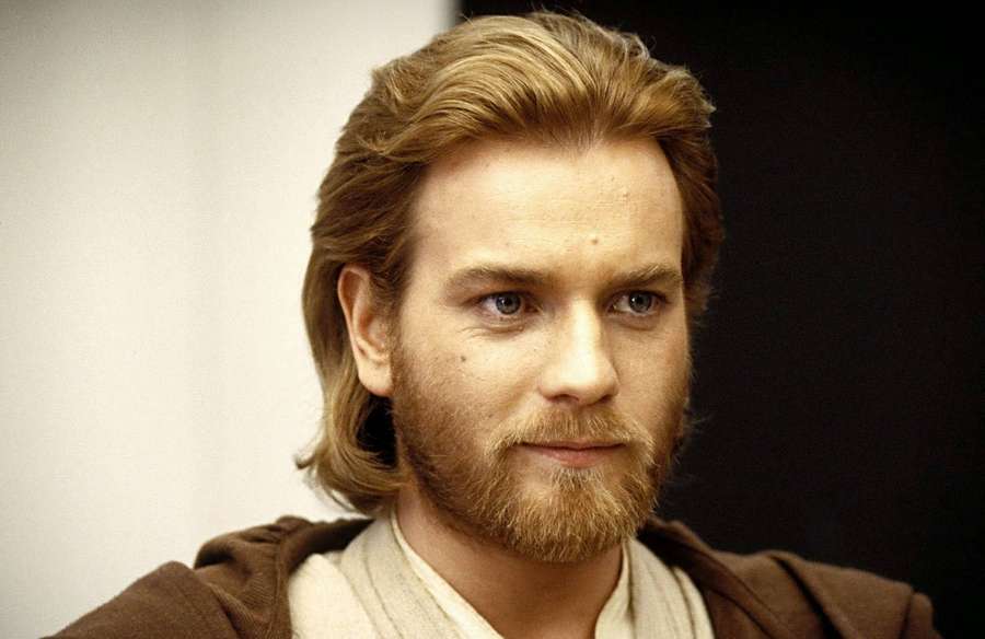 A man with blond hair and beard in Jedi robes looks directly at the camera. — Ewan mcgregor Wallpaper