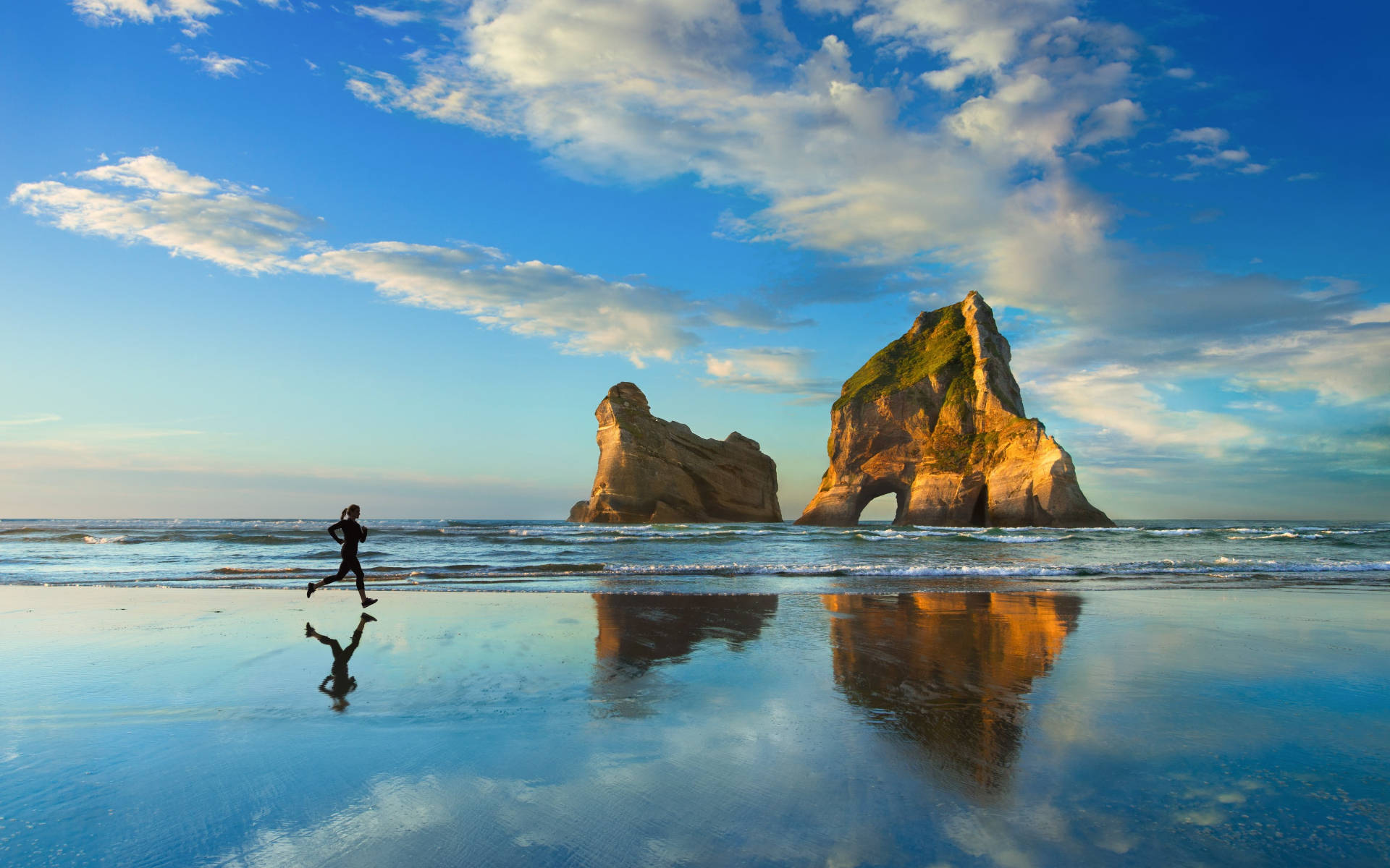 Um corredor numa praia molhada com pilares marinhos e reflexos do céu ao pôr do sol. — Executando Papéis de Parede