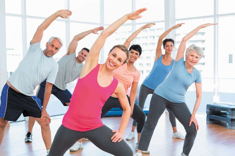 Seniors and adults doing stretching exercises in a well-lit fitness studio. — Exercise Picture