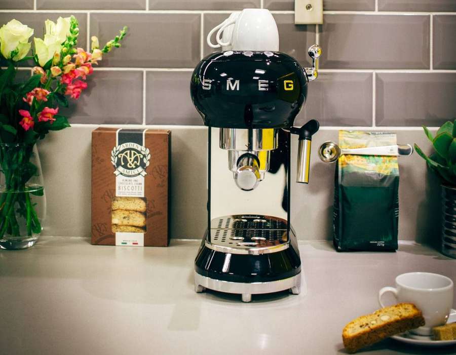 Máquina de espresso negra con biscotti y flores en la encimera — Exprimidor Fondos de pantalla