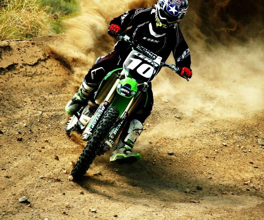 Piloto de motocross em moto verde levantando poeira em trilha de terra — Extremo Papéis de Parede