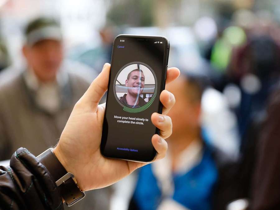 Hand holding phone with face recognition setup screen showing smiling man and instructions. — Face Id Wallpaper