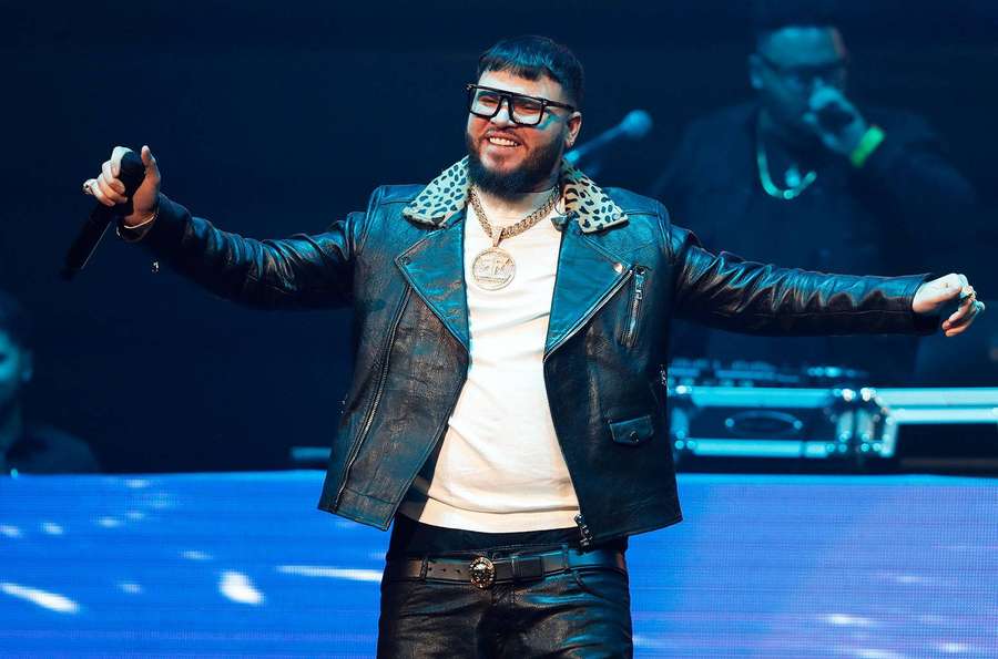 Artista masculino en el escenario con chaqueta de cuero y gafas sosteniendo un micrófono. — Farruko Fondos de pantalla