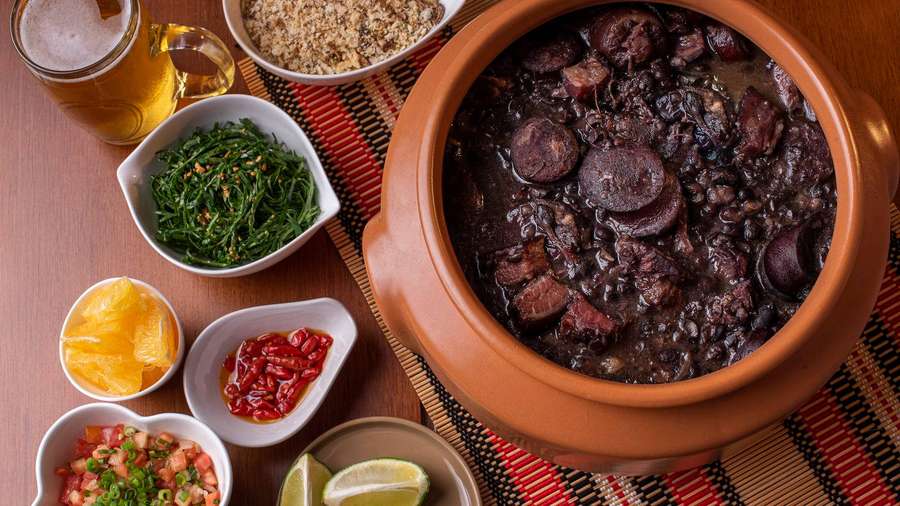 Brazilian feijoada stew with side dishes and beer on wooden table — Feijoada Wallpaper