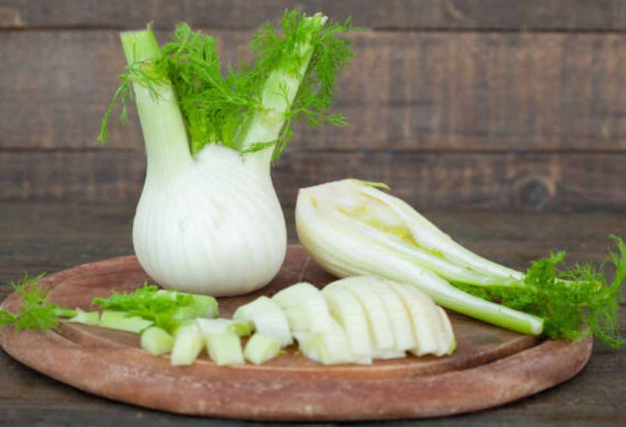 Fresh fennel bulbs and sliced pieces on a wooden cutting board. — Fennel Wallpaper